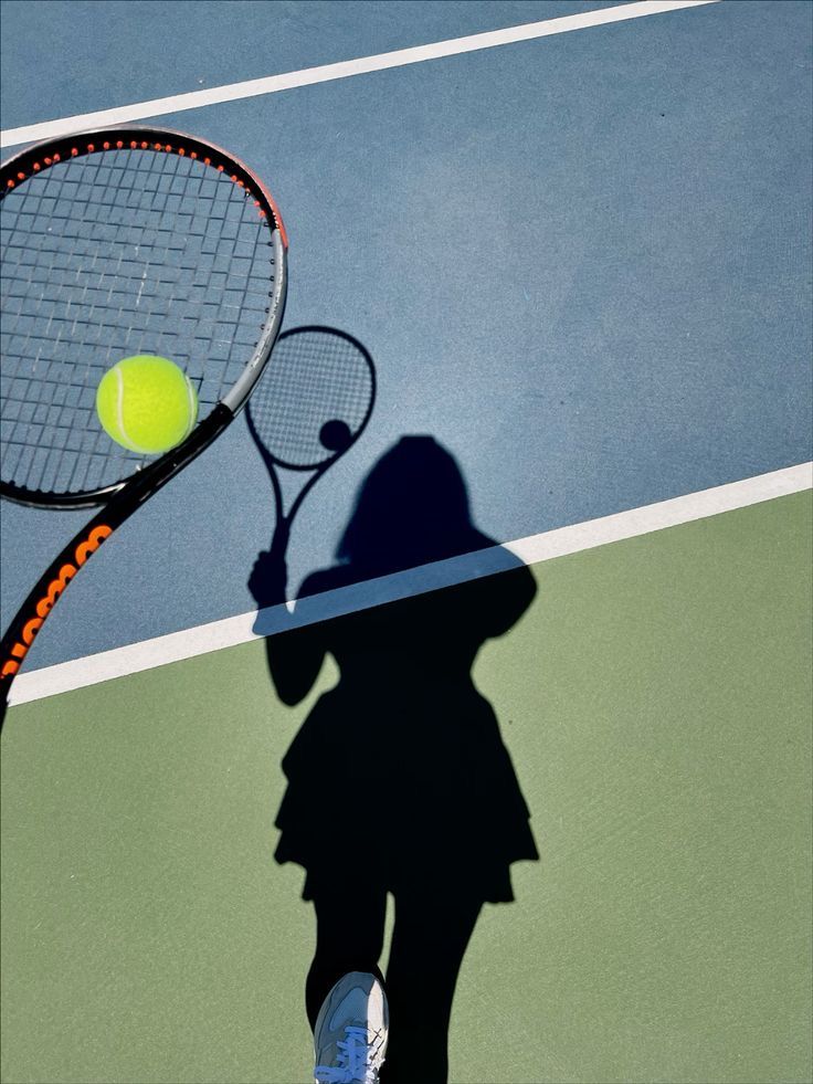 A tennis player's shadow on a sunlit court, racket and ball mid-rally